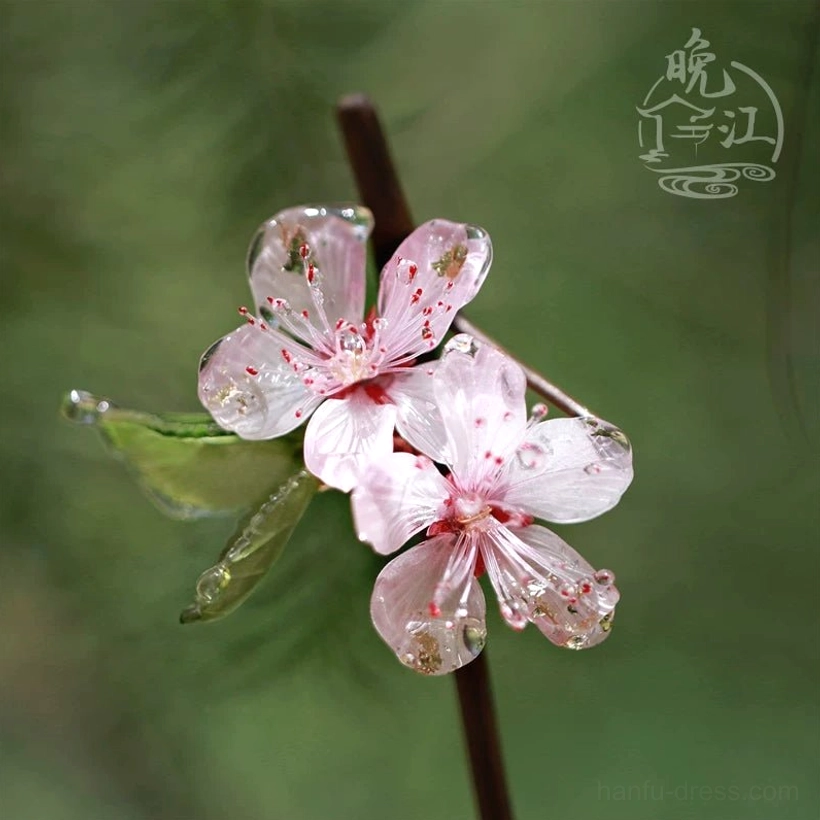 Side close-up of peach blossom Chinese hairpin with translucent pink flowers, red stamens, green resin leaves, and dew-like petal details