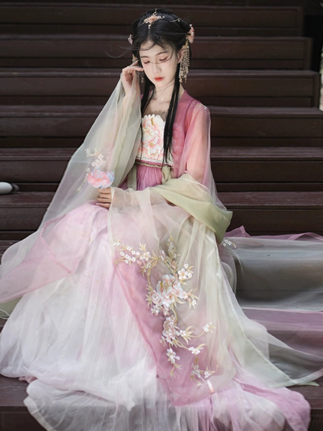 Model seated in a Peach Blossom God Tang Dynasty Hanfu dress displaying the long pink skirt, embroidered side details, and elegant flowing train
