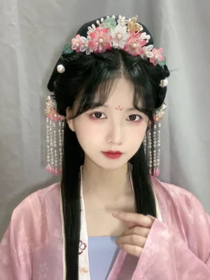 Model wearing peach blossom Hanfu hair accessory set with long tassel hairpins and floral crown styling with a pink Song style Hanfu outfit