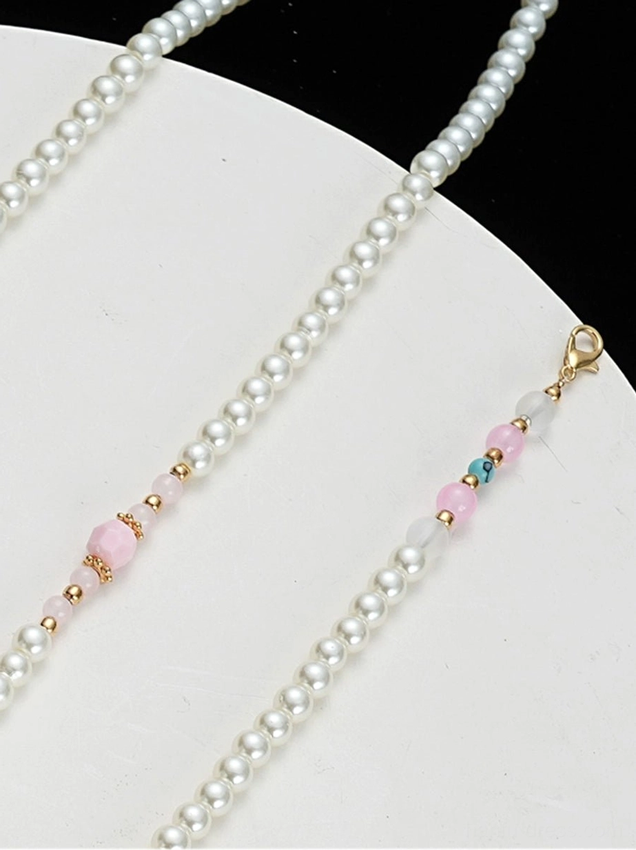 Pearl chain and lobster clasp detail of peach butterfly Chinese necklace with pink beads gold spacers and turquoise accent beads on white background