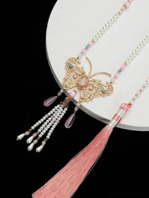 Overhead view of peach butterfly Chinese yingluo necklace with pearl strands colorful beads gold butterfly pendant and soft pink tassel