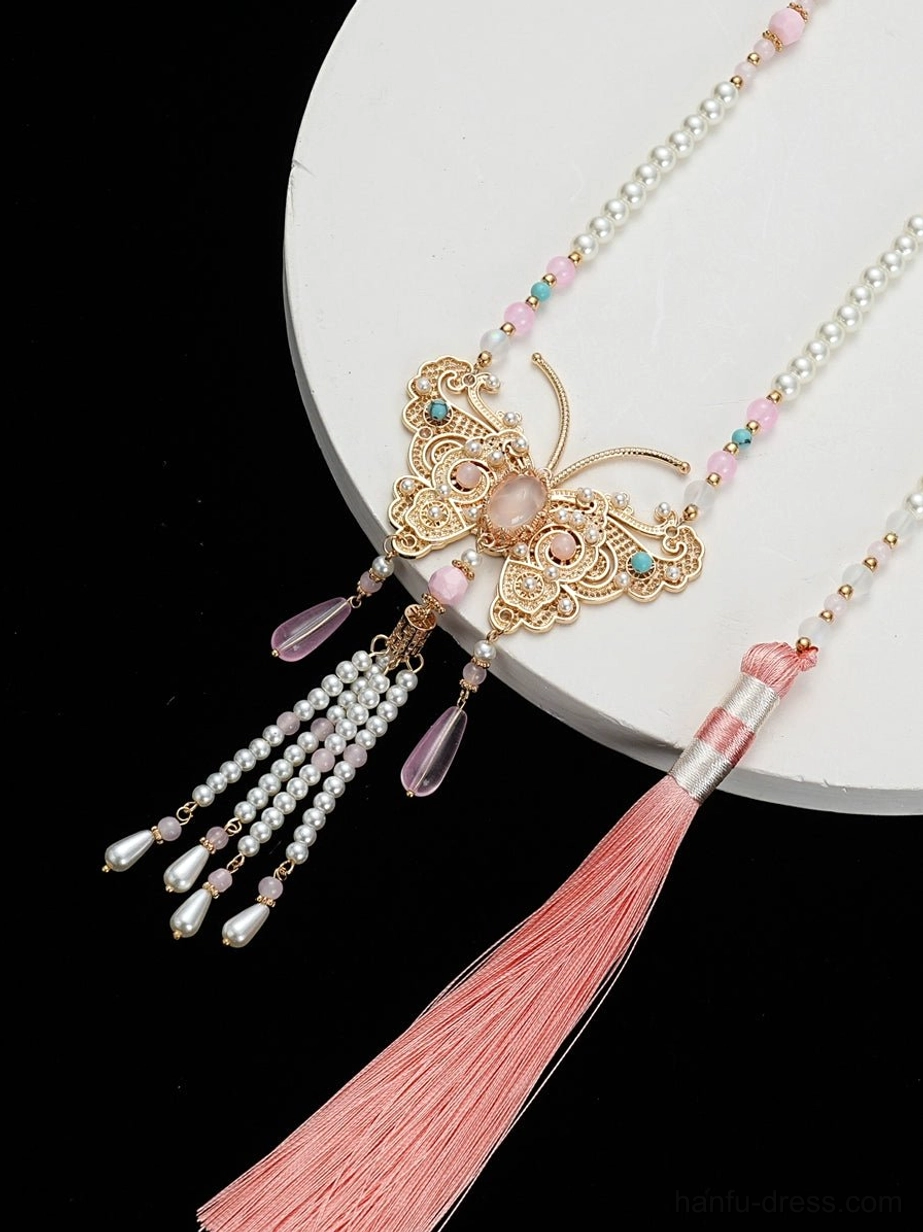 Overhead view of peach butterfly Chinese yingluo necklace with pearl strands colorful beads gold butterfly pendant and soft pink tassel