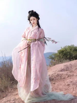 Full-body front view of a Peach Oolong Wei Jin Dynasty Qiyao Ruqun Hanfu with peach-pink cross-collar top, pale green sheer trailing fabric, golden waist sash and wide flowing sleeves