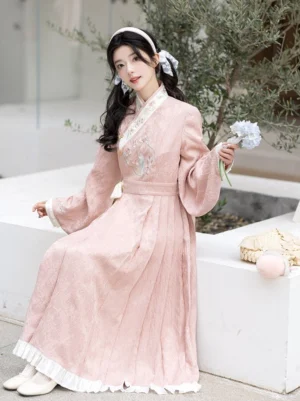Pink modern Hanfu cross-collar spring dress with white ruffle hem and peach rabbit embroidery worn in an outdoor courtyard
