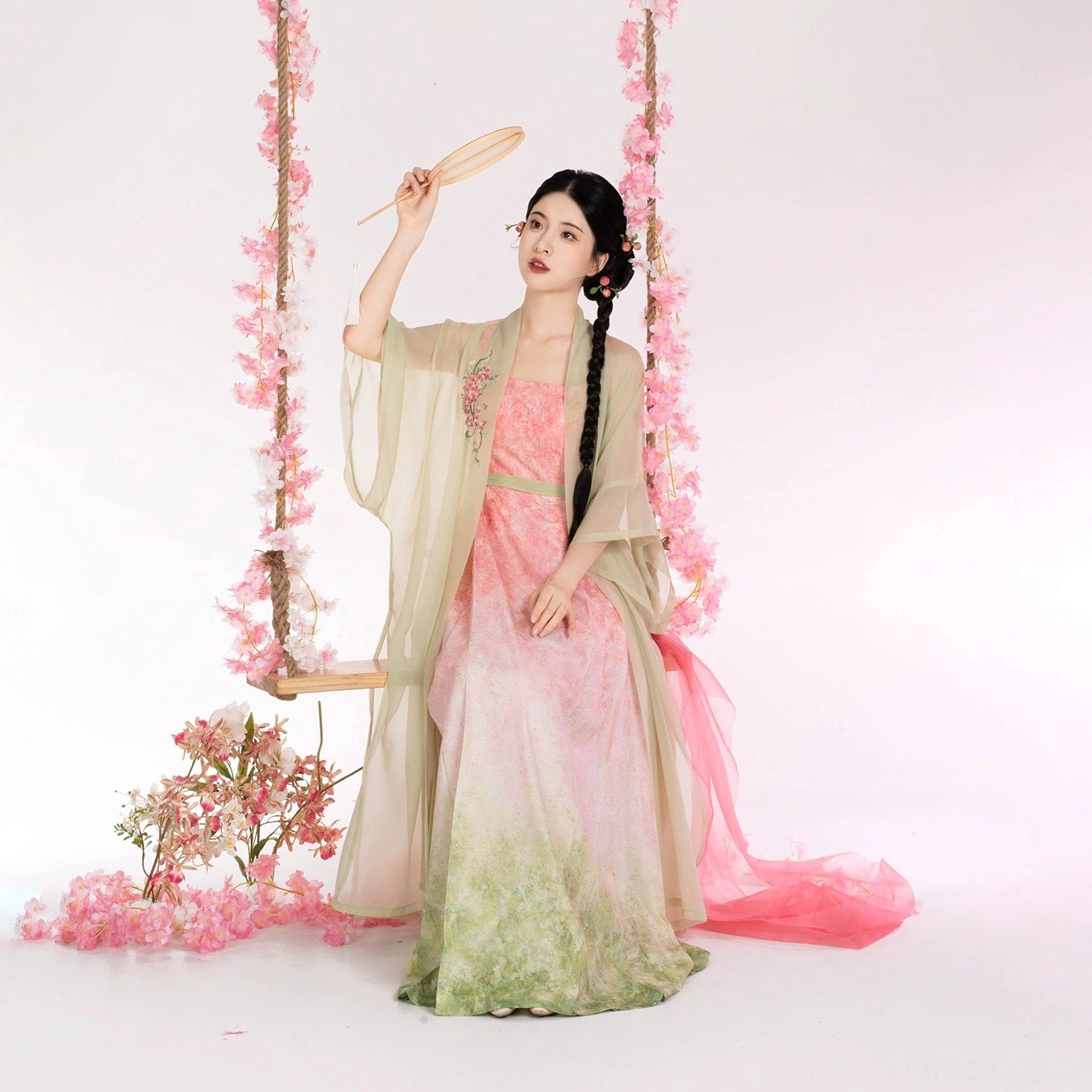 Woman lifting a traditional handheld fan while wearing a floor-length Peach Willow Branch Hanfu set with a romantic pastel beizi jacket and gradient dress