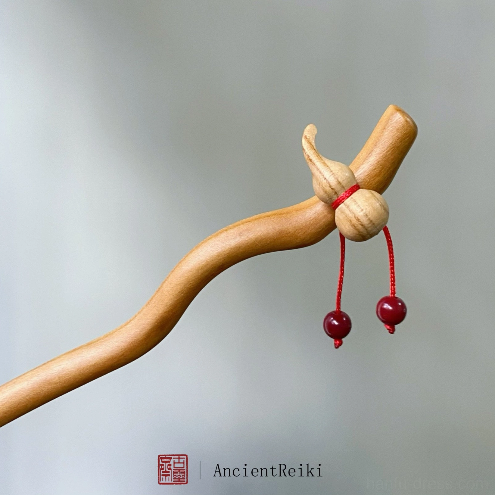 Peach wood hulu Chinese hair stick with natural gourd ornament red cord and dangling cinnabar beads on gray background