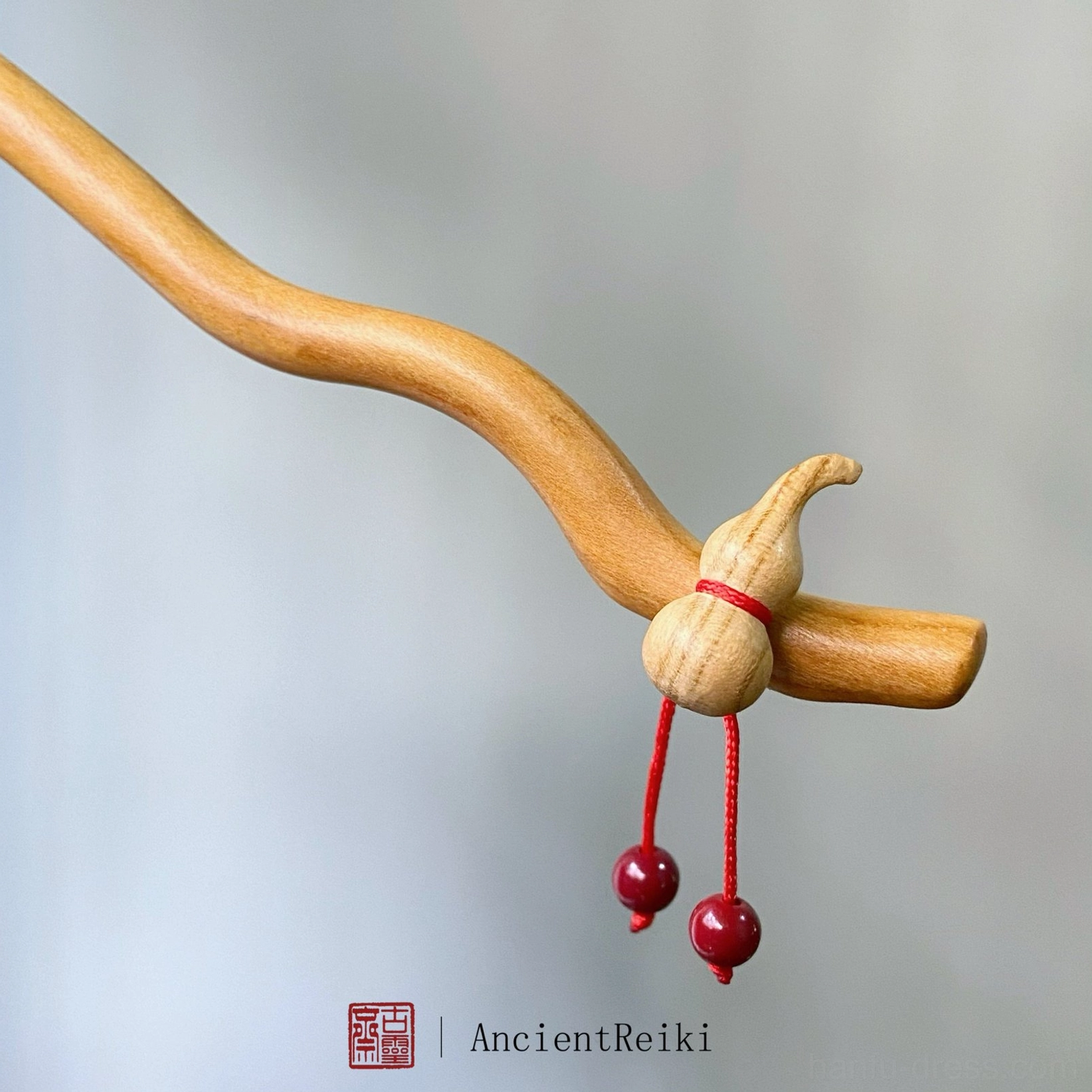 Close-up of hulu gourd ornament on peach wood Hanfu hair stick with red cord and two dangling cinnabar beads