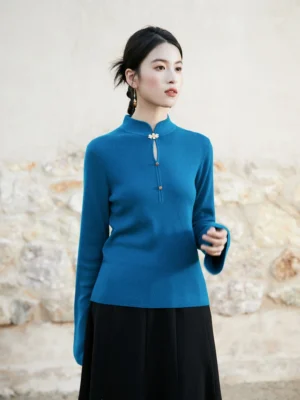 Peacock blue modern Hanfu knitted sweater with mandarin stand collar traditional Chinese frog button and flared long sleeves shown in a close-up outdoor portrait