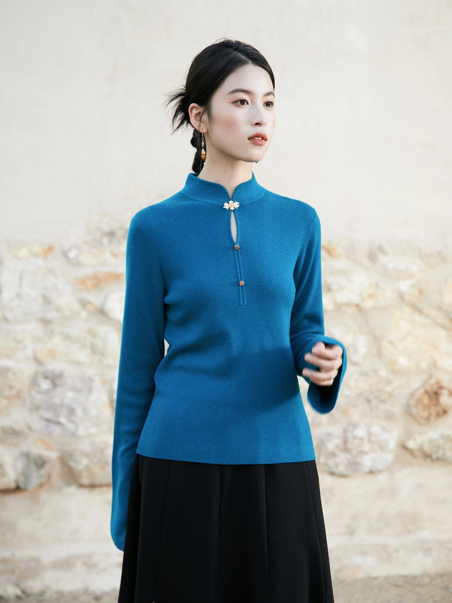 Peacock blue modern Hanfu knitted sweater with mandarin stand collar traditional Chinese frog button and flared long sleeves shown in a close-up outdoor portrait