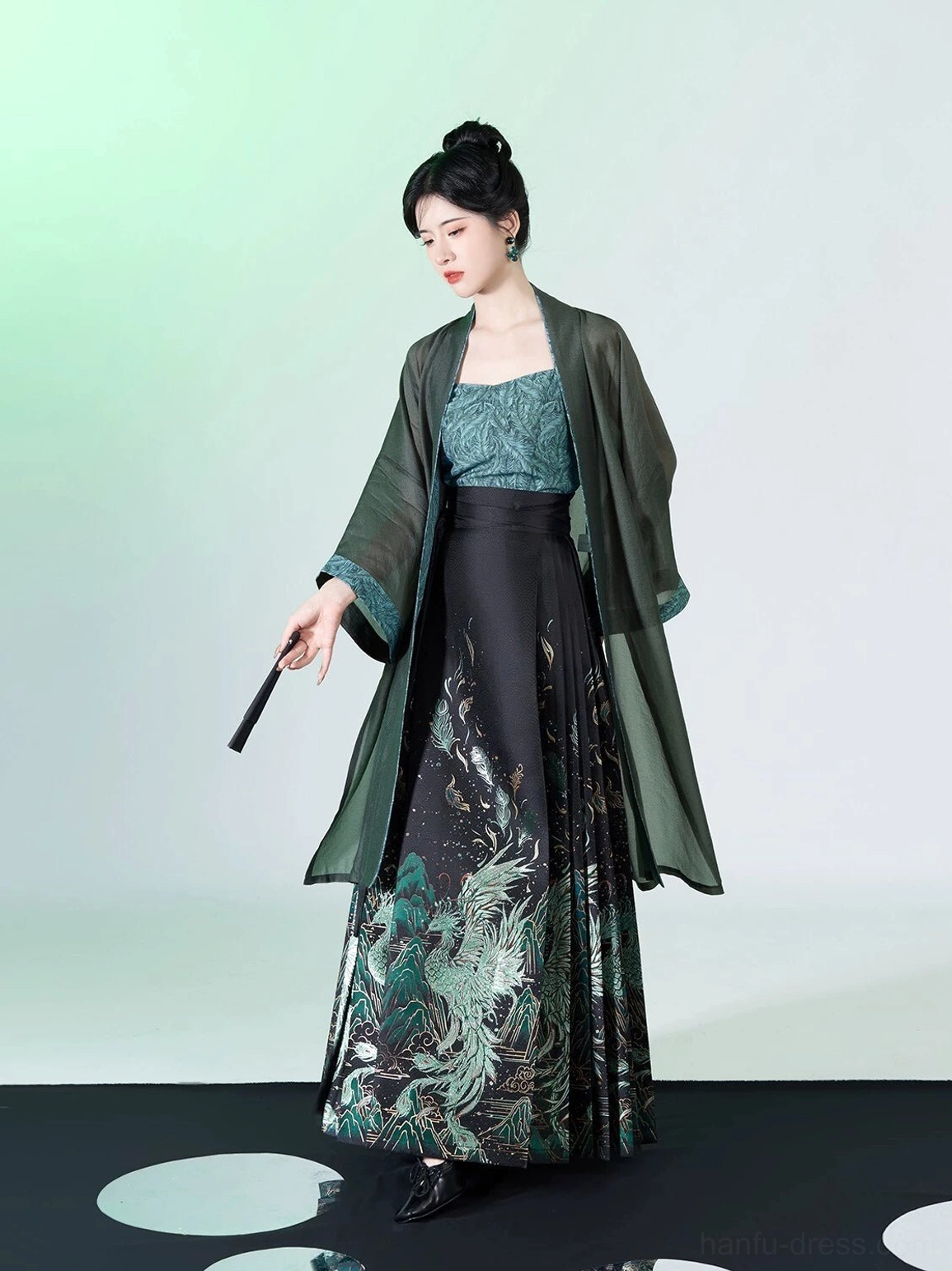 Three-quarter view of teal and black peacock feather Ming Dynasty Hanfu outfit styled with a traditional folding fan