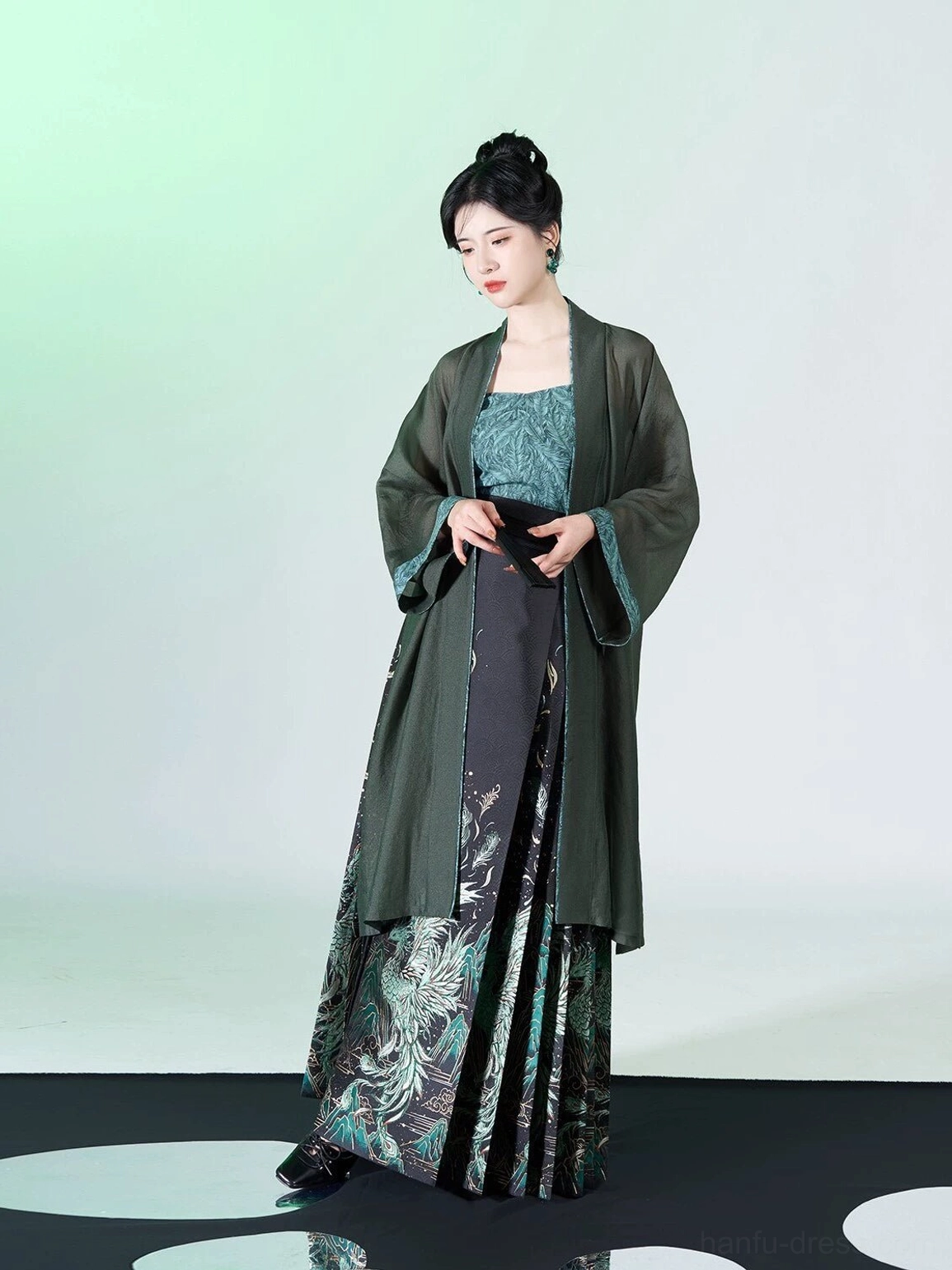 Side view of black mamian skirt with teal peacock and phoenix inspired motifs paired with a sheer green Hanfu overcoat