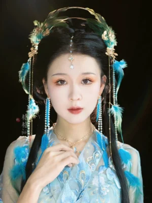 Peacock Queen Hanfu hair accessory set worn with light blue embroidered Hanfu, featuring a blue green feather crown, gold ornaments, beaded tassels, and forehead pendant