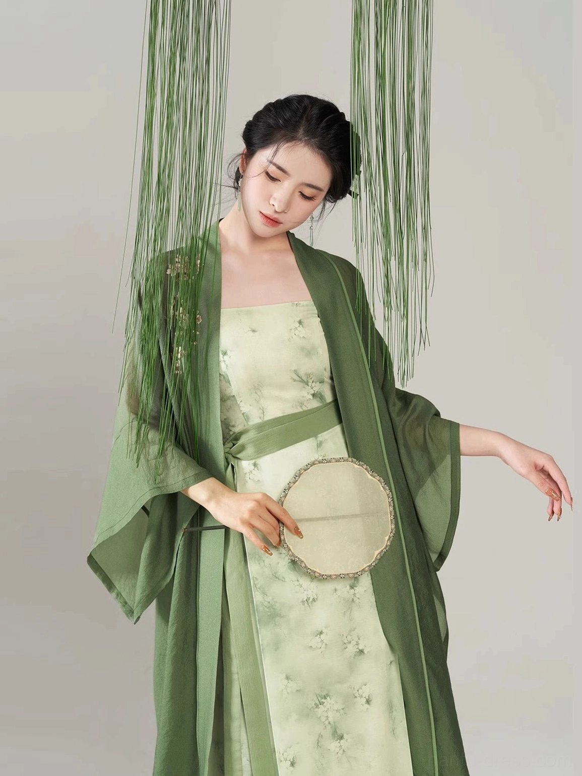 Close up of Pear Blossom Begonia modern Hanfu showing floral printed linen blend dress, embroidered green overcoat shoulder and round silk fan