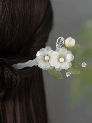Back view of pear blossom Chinese hair stick worn in a dark hair half-up low bun hairstyle