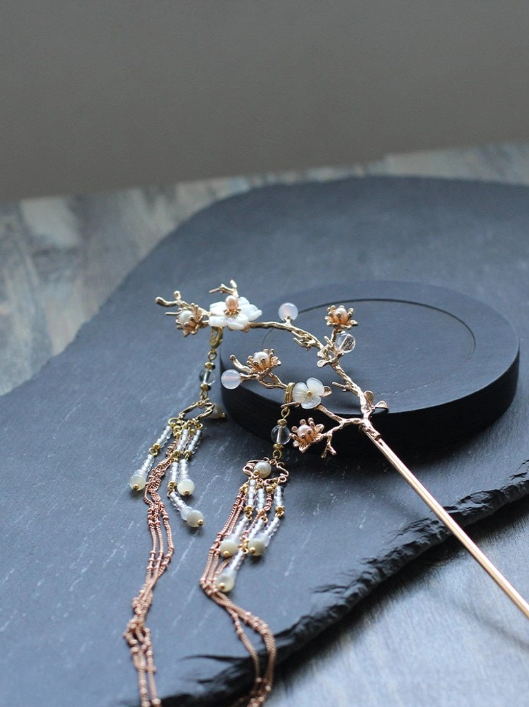 Reverse view of pear blossom Chinese hair pin with white flower branch ornament and matching layered tassel chains displayed on dark stone