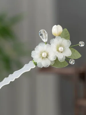 Pear blossom cloud Chinese hair stick close-up with translucent white shaft, organza flowers, pearl centers, green leaves, and crystal tassels
