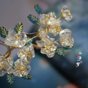 Close-up of a Pear Blossom Fragrance Chinese hairpin with clear flower blossoms gold-tone branches and teal enamel leaves