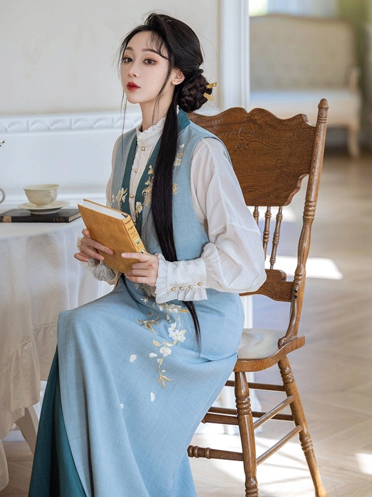 Model wearing a modern Chinese style Pear Blossoms Hanfu outfit with embroidered vest and high-waisted long skirt in a vintage indoor setting
