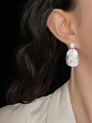 Close-up of a woman wearing pearl shell tassel drop earrings with iridescent shell discs and long silver chains for Hanfu jewelry styling