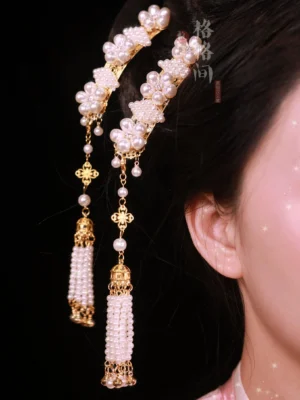 Close-up side view of traditional Chinese pearl tassel hair pins worn in a hairstyle, featuring pink and white pearl flower clusters, gold-tone metal accents, and long hanging tassels