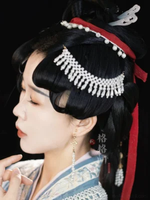Side profile of a model wearing pearl tassel Hanfu hair pin with a red hair ribbon and white jade style hair ornament in a traditional Chinese updo