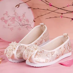 Champagne gold pearl tassel traditional Chinese Hanfu shoes for women displayed from a side overhead view with floral jacquard fabric, white trim, round toes, and white rubber soles