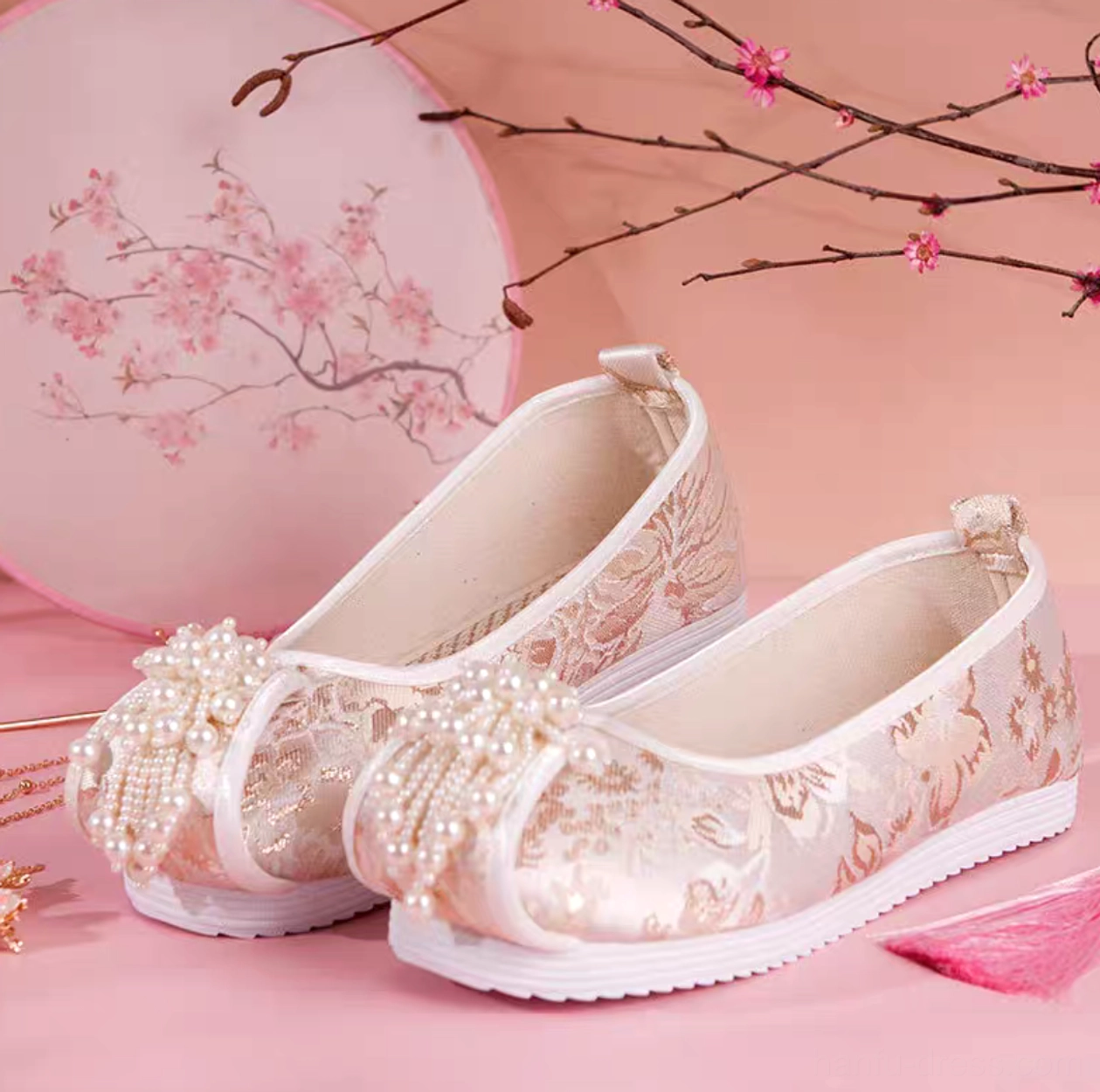 Champagne gold pearl tassel traditional Chinese Hanfu shoes for women displayed from a side overhead view with floral jacquard fabric, white trim, round toes, and white rubber soles