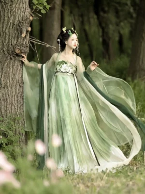 Three-quarter rear view of a woman wearing a peppermint green Tang Dynasty Hanfu Heziqun dress with gradient pleated skirt, sheer big sleeve coat, embroidered details, dark green sash, and flowing train in a woodland setting