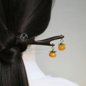 Handmade persimmon Chinese hair stick with dark ebony-toned antler-inspired wooden body, orange hanging persimmon charms, and gold-tone details styled in a loose Hanfu hairstyle