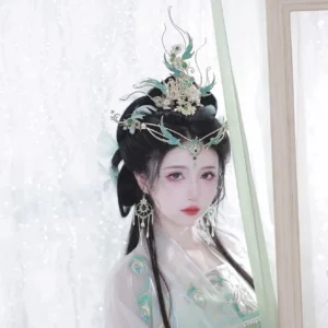 Model wearing Phantom Bird hanfu hair accessories with gold filigree crown, turquoise accents, green gemstones, and white floral ornaments