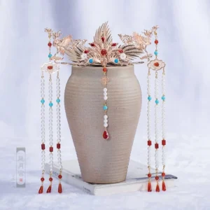 Complete phoenix flame Hanfu hair accessory set with gold tone crown, matching side hairpins, red blue jewel accents and beaded tassels displayed on ceramic vase