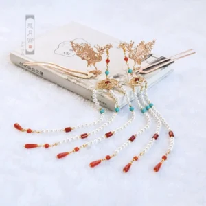 Pair of gold tone phoenix Hanfu hairpins with red and blue decorative stones, long beaded tassels and red teardrop pendants on book display