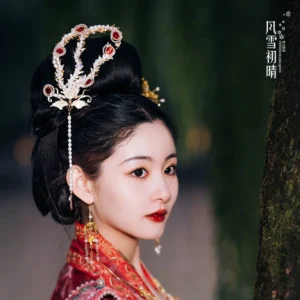 Phoenix Hanfu hair crown worn by a woman in traditional Chinese clothing, featuring gold-tone filigree, red faux gemstones, imitation pearls, and a long pearl tassel in a woodland portrait