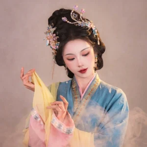 Female model wearing a phoenix and peony Hanfu hair accessories set with pastel pink and blue floral ornaments, gold-toned hairpins, dangling tassels, and matching traditional Chinese earrings