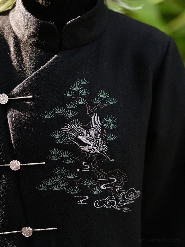 Close-up detail of intricate pine crane and cloud embroidery on a black tweed Chinese style coat with metal toggle fasteners