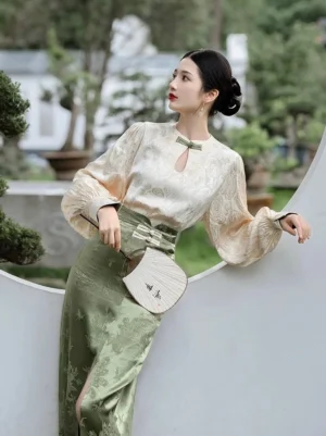 Rear three-quarter view of pine green modern Hanfu cheongsam two-piece set with cream lantern sleeve top in a classical Chinese garden