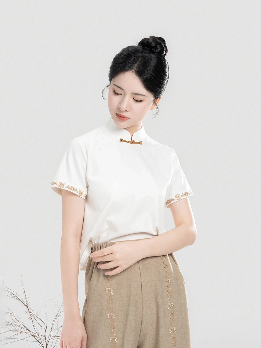 Front detail of Pinewood modern Hanfu top featuring Chinese frog fastening embroidered sleeve cuffs and khaki pants