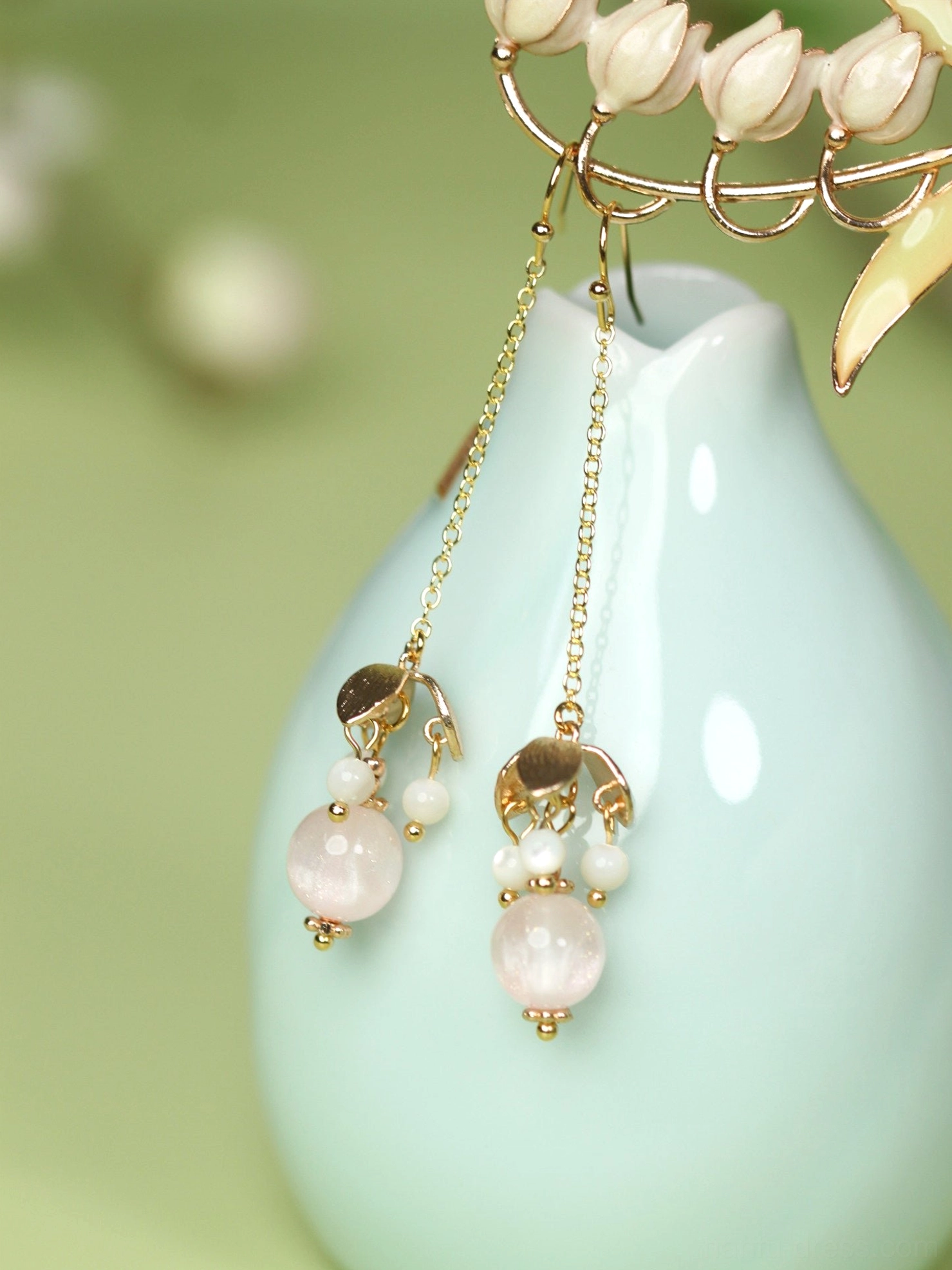 Pink beaded long dangle Chinese Hanfu earrings displayed beside a pale cyan ceramic vase with gold tone chains and white bead accents