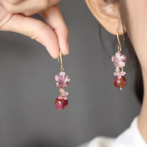 Woman wearing pink flower and burgundy bead Chinese drop earrings with gold hook closure in close-up side view