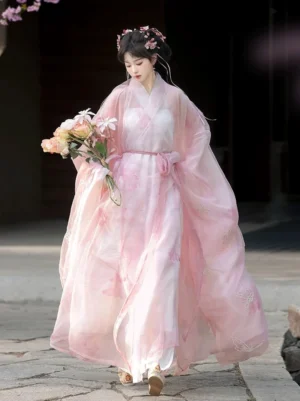 Pink butterfly Han Dynasty inspired Hanfu robe set worn outdoors, showing flowing sheer wide sleeves, floral embroidery, cross-collar layers, and waist sash