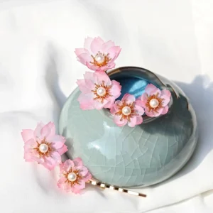 Five piece pink cherry blossom hanfu hair pin set with pearl centers and gold tone pins displayed on a celadon jar