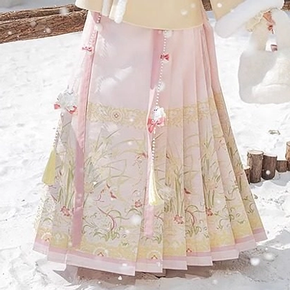 Close-up of pink embroidered Mamian skirt with traditional pleats, botanical floral patterns, tassel pendants, and ruffled hem