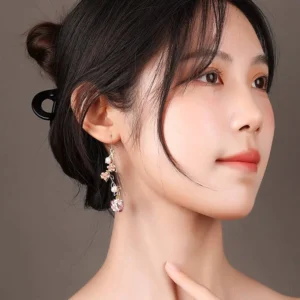 Pink enamel floral drop Chinese earring worn on an East Asian woman showing the elegant hook earring style and delicate garden vine design