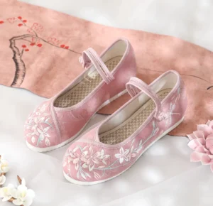 Dusty pink floral embroidered Hanfu shoes with ankle strap, canvas upper and round toe shown in Chinese style flat lay