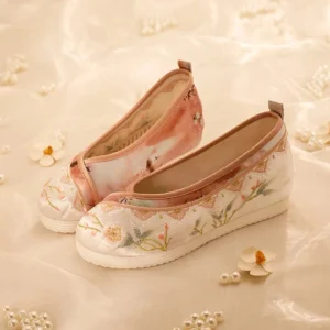 Pink and ivory floral embroidered Hanfu shoes for women with brown trim and low hidden wedge rubber soles, displayed on satin fabric with flowers and pearls