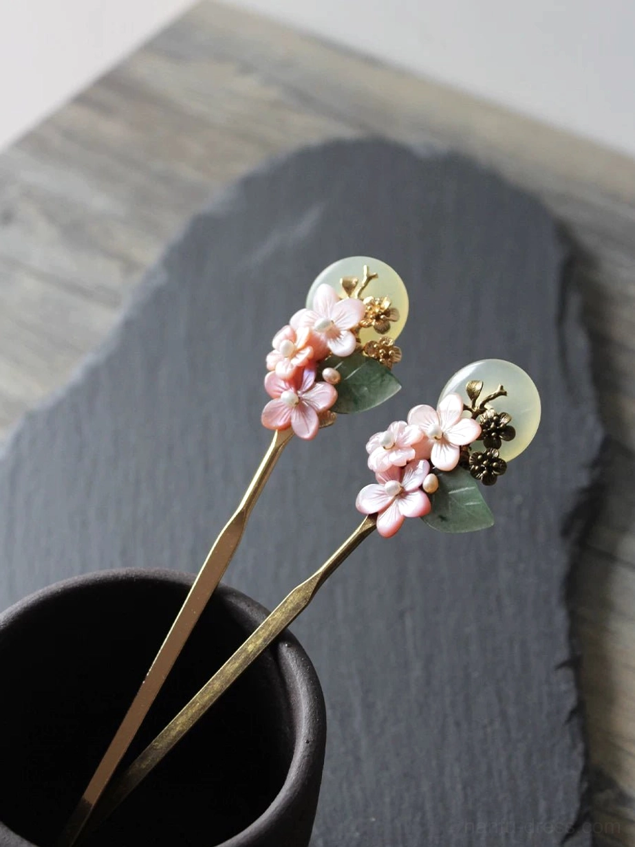 Matching pink floral Chinese Hanfu hair sticks with jade-inspired moon pendants and antique bronze finish displayed in a dark ceramic cup