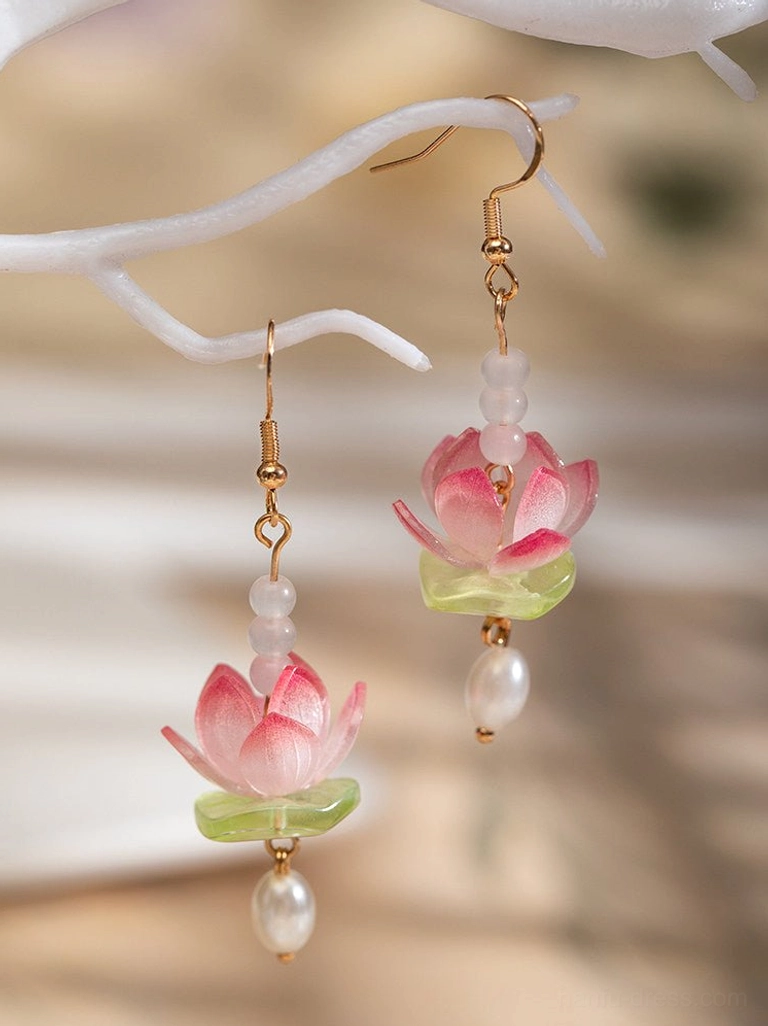 Pink lotus drop hanfu earrings with gold ear hooks, green leaf accents, white beads, and freshwater pearl pendants displayed on a decorative branch