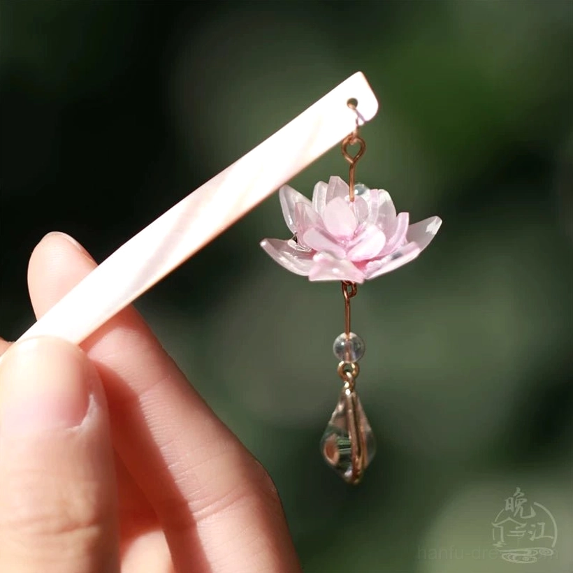 Pink lotus themed Chinese hair stick with pearlescent pin and hanging floral pendant shown in a low side close-up