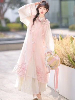 Front view of pink Ming Dynasty hanfu two piece set with floral vest, beige flowing robe, wide sleeves, front buttons, tassel details, and modern Chinese fashion styling