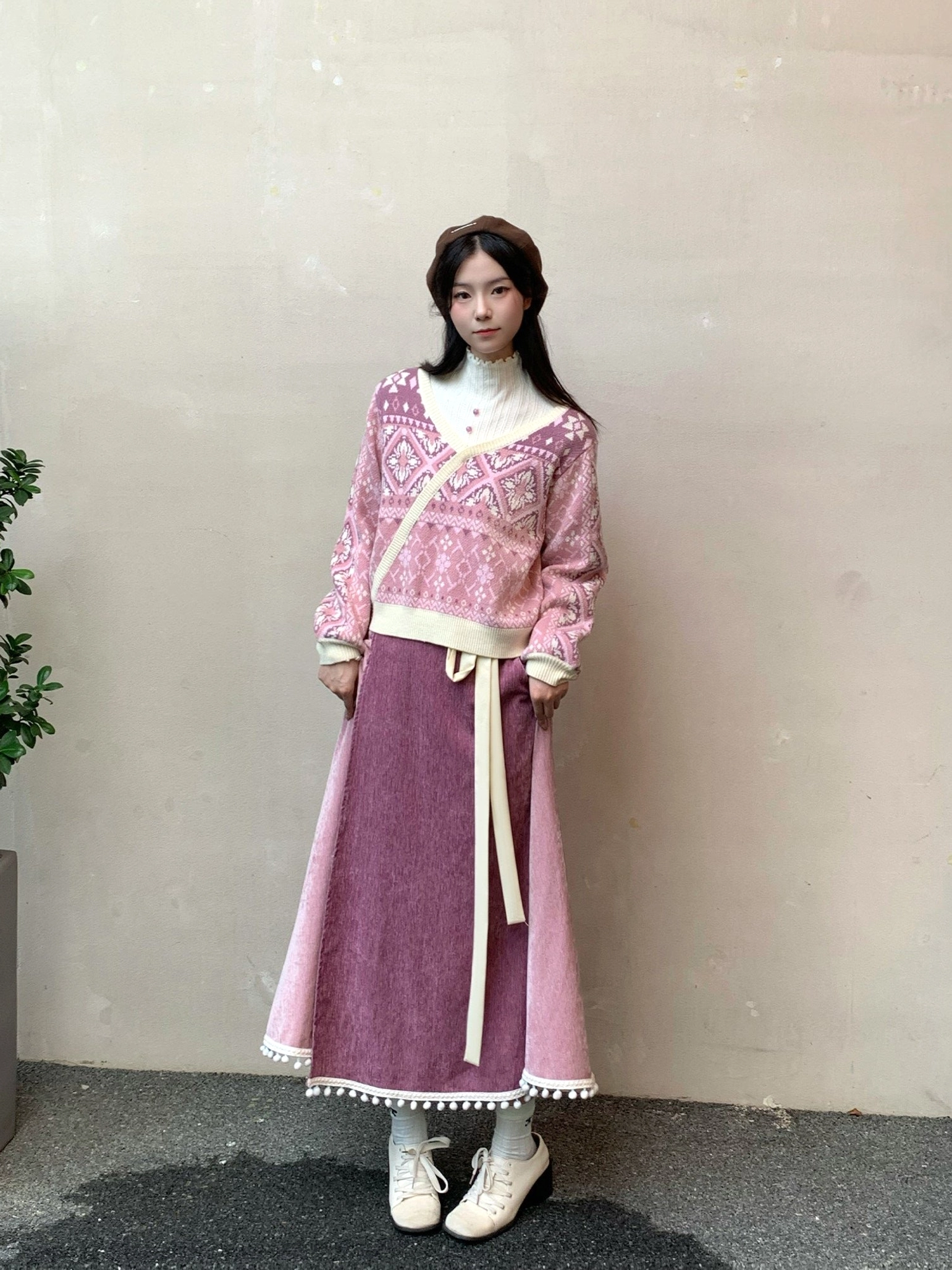 Full-body front view of a pink modern Chinese-style knitted sweater outfit with cream contrast trim, mauve skirt, and beret